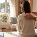 Un magnétiseur posant les mains sur les épaules d'une femme assise, en thérapie énergétique à Nice.